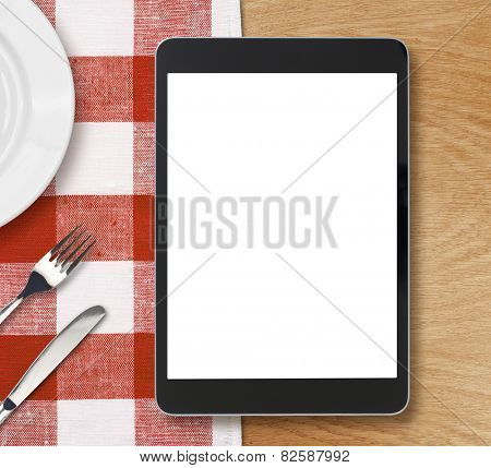black tablet pc or ipad on dinner table with blank screen