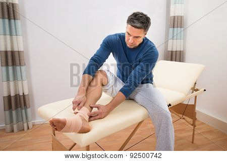 Man Tying Bandage To His Foot