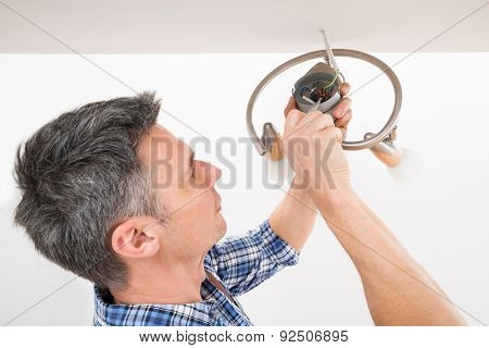 Electrician Fixing Light On Ceiling