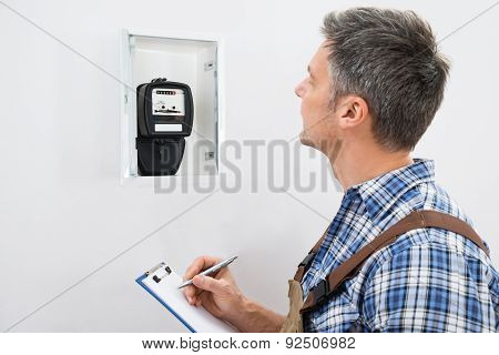 Technician Taking Reading Of Electric Meter