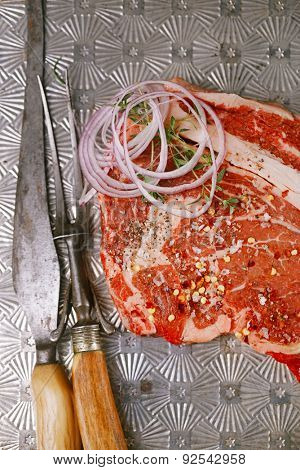 beef steak t-bone with vintage meat fork and knife on metal backdrop