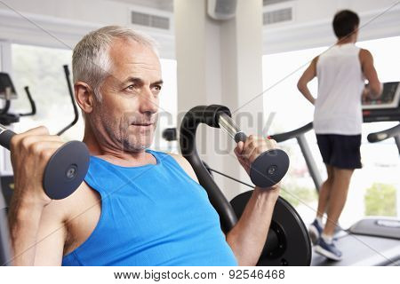 Man Using Weights Machine With Runner On Treadmill In Background