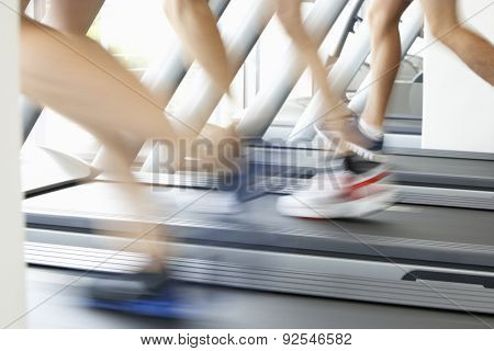 Close Up Of 3 Runners Feet On Running Machine In Gym