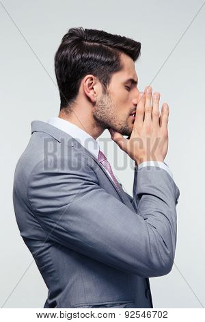 Side view portrait ofa  businessman praying over gray background