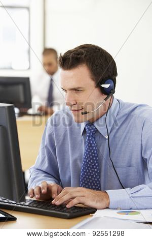 Friendly Service Agent Talking To Customer In Call Centre