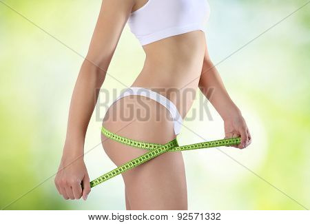 Bum And Legs Of Slim Woman Over Green Background With Meter