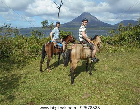 two Tourists riding horseback against the Background of a vulcano