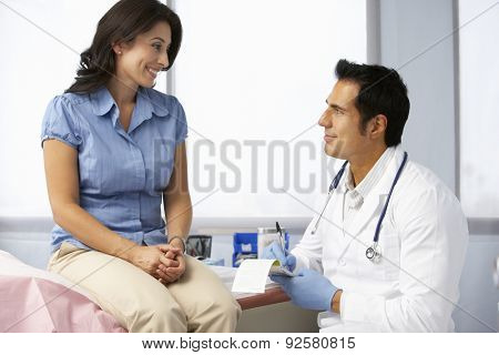 Doctor In Surgery With Female Patient Writing Prescription