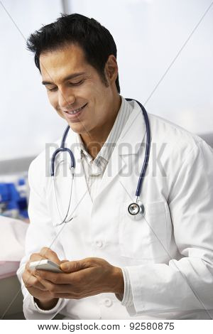Male Doctor In Surgery Using Mobile Phone
