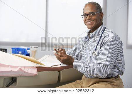 Male Doctor In Surgery Using Mobile Phone
