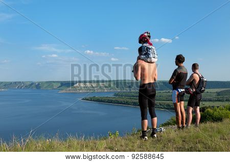 Three Tourists With  Small Child Standing On Shore Beautiful Reservoir