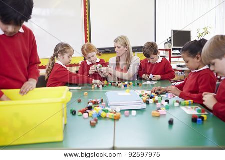 Pupils And Teacher Working With Coloured Blocks