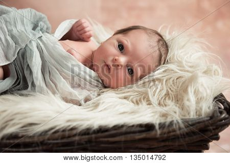 Newborn baby with big eyes is in the basket