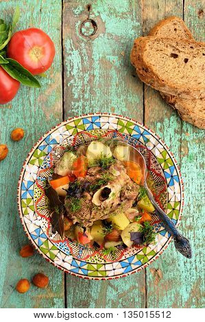 Homemade chorba soup with lamb meat on bone potato carrots and dried apricots served with rye bread vertical