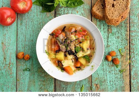 Chorba soup with lamb ribs potato carrots and dried apricots served with rye bread overhead view