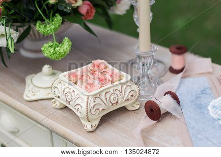 Pink roses in a ceramic box on the table, beautiful ribbons