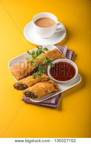 spring rolls or kothimbir vadi or sambar vadi or coriander spring rolls, indian snacks, tastes great with tea and tomato ketchup or tomato sauce, in square white plate over colourful background