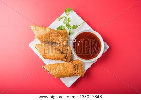 spring rolls or kothimbir vadi or sambar vadi or coriander spring rolls, indian snacks, tastes great with tea and tomato ketchup or tomato sauce, in square white plate over colourful background