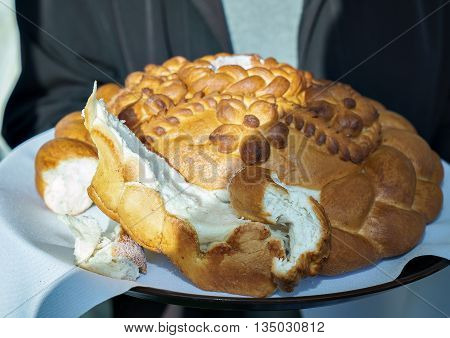 Wedding. A man dressed in a black jacket holds a lush delicious loaf with a tablecloth. Accutanee pieces of the loaf lie side by side on a white saucer