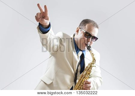 Music Concepts and Ideas. Portrait of Hadnsome Male Saxophone Player Showing V Sign Whilst Playing in Studio Environment. Horizontal Image Orientation