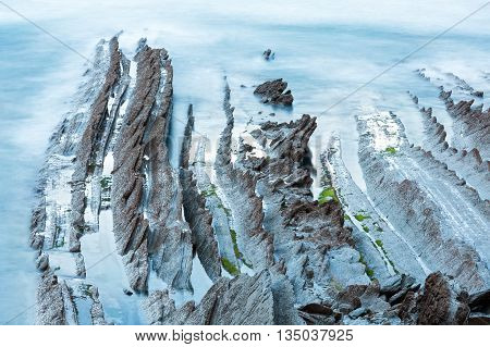 Twilight Ocean Coast With Ribbed Stratiform Rock.