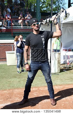 ARLINGTON, TX - APR 18: Recording artist Luke Bryan poses with a bow at the ACM & Cabela's Great Outdoor Archery Event at the Texas Rangers Youth Ballpark on April 18, 2015.