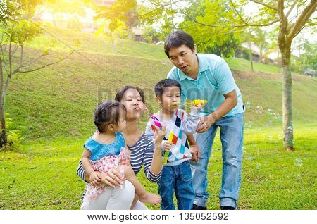 Asian family blowing bubbles outdoor at park