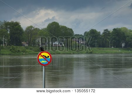 Polnad Kraków flooded Vistula/Wisła river embankments no swimming sign over the water with a crow sitting on