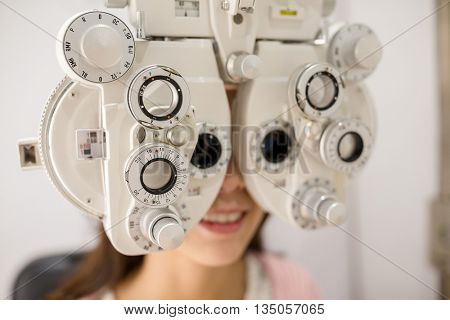 Female patient looking through phoropter during eye exam
