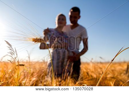 Happy and young pregnant couple hugging in nature