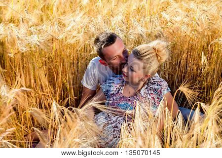 Happy and young pregnant couple hugging in nature