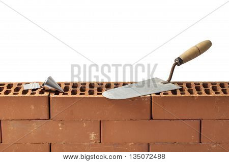 Construction tools trowel and plumb bob left on a new brickwork isolated on white.