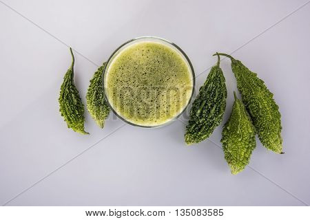 Herbal juice of green momodica in a glass with sliced vegetables, karela juice or bitter gourd juice