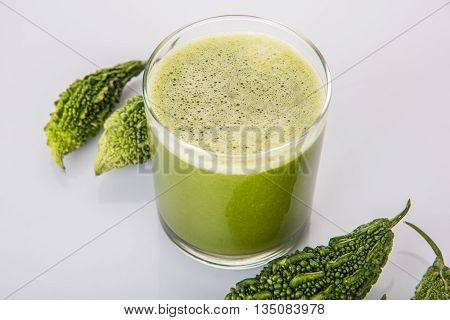 Herbal juice of green momodica in a glass with sliced vegetables, karela juice or bitter gourd juice