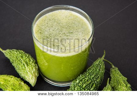 Herbal juice of green momodica in a glass with sliced vegetables, karela juice or bitter gourd juice