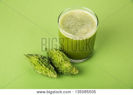 Herbal juice of green momodica in a glass with sliced vegetables, karela juice or bitter gourd juice