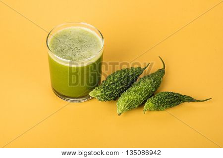 Herbal juice of green momodica in a glass with sliced vegetables, karela juice or bitter gourd juice