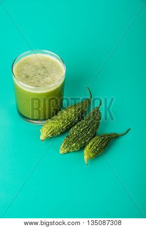 Herbal juice of green momodica in a glass with sliced vegetables, karela juice or bitter gourd juice