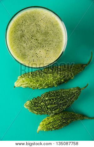 Herbal juice of green momodica in a glass with sliced vegetables, karela juice or bitter gourd juice