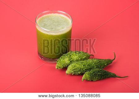 Herbal juice of green momodica in a glass with sliced vegetables, karela juice or bitter gourd juice