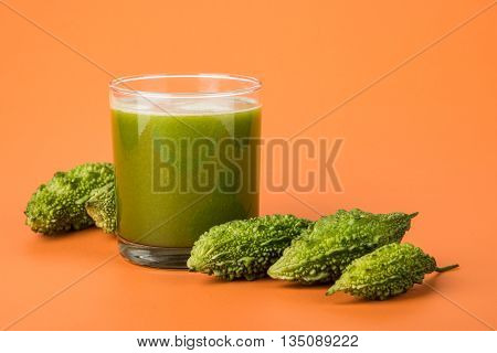 Herbal juice of green momodica in a glass with sliced vegetables, karela juice or bitter gourd juice