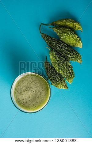 Herbal juice of green momodica in a glass with sliced vegetables, karela juice or bitter gourd juice