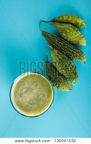 Herbal juice of green momodica in a glass with sliced vegetables, karela juice or bitter gourd juice