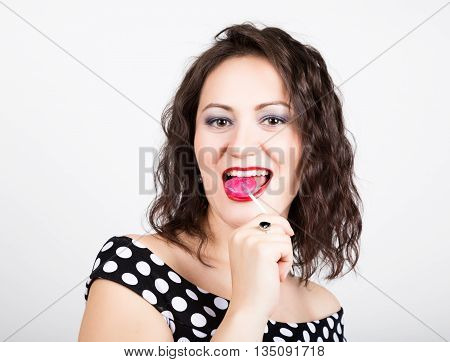 Portrait of happy beautiful young woman licking chupa chups. pretty woman with heart shaped lollipop.