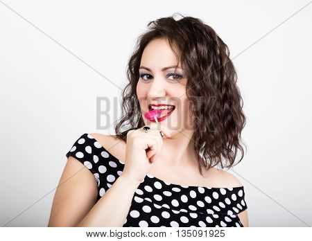 Portrait of happy beautiful young woman licking chupa chups. pretty woman with heart shaped lollipop.