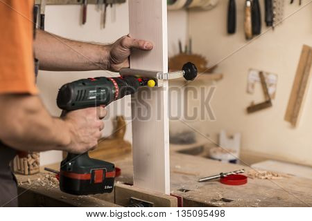 Hands of a carpenter with drill and tools