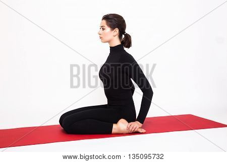 Beautiful athletic girl in black suit doing yoga. Virasana asana hero pose. Isolated on white background.
