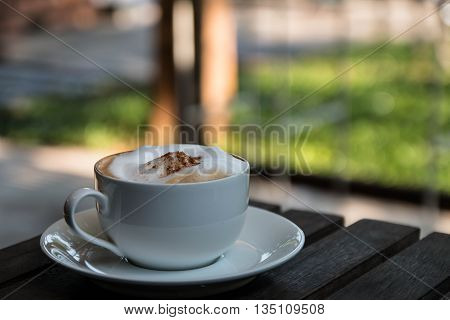 Hot Cappuccino in the cup on wood table