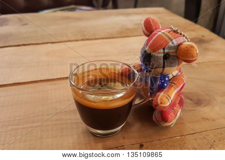 Coffee on wooden background and bear doll