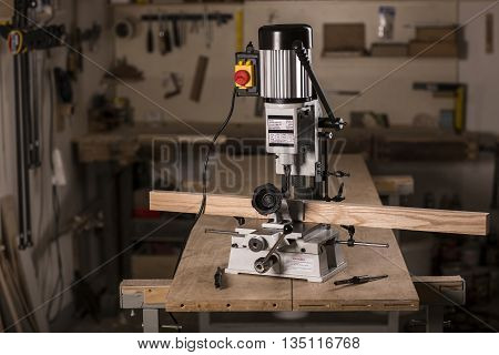 Mortiser machine on the wooden workbench in carpentry